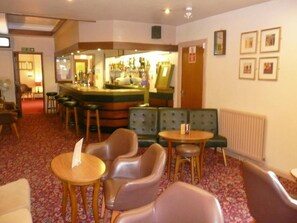 A hotel lobby with seating areas, a bar, and framed pictures on the wall.