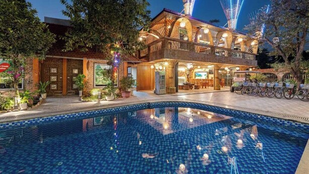 Ein Hotel mit Pool, Sitzgelegenheiten im Freien und einem Riesenrad im Hintergrund.