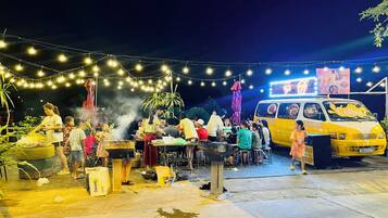 An outdoor dining area with string lights, a food truck, and a crowd of people.