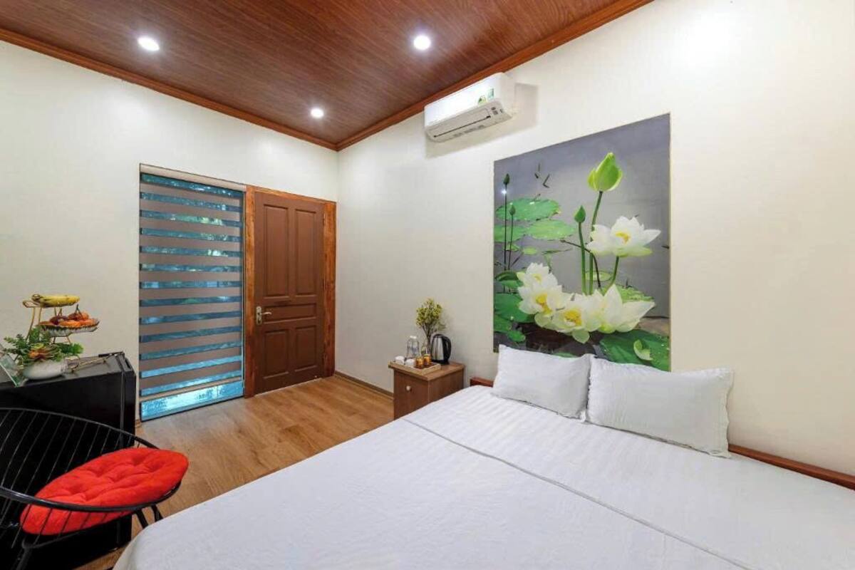 A bedroom with a bed, a nightstand, a chair, a painting of flowers, and a door with a striped pattern.