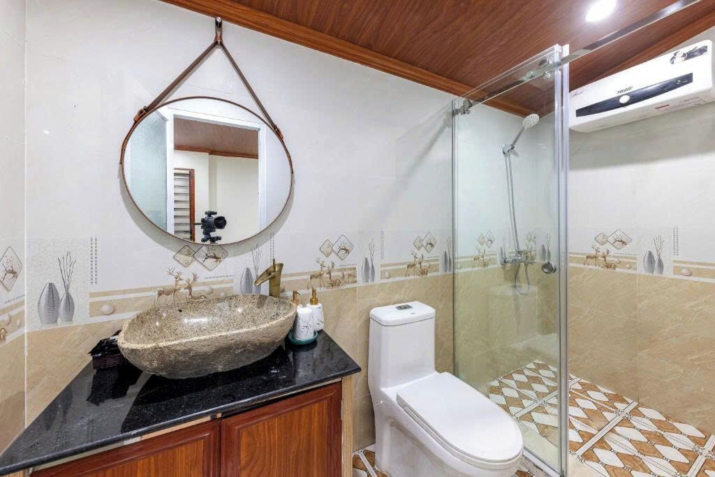 A bathroom with a stone sink, a toilet, and a glass shower enclosure.