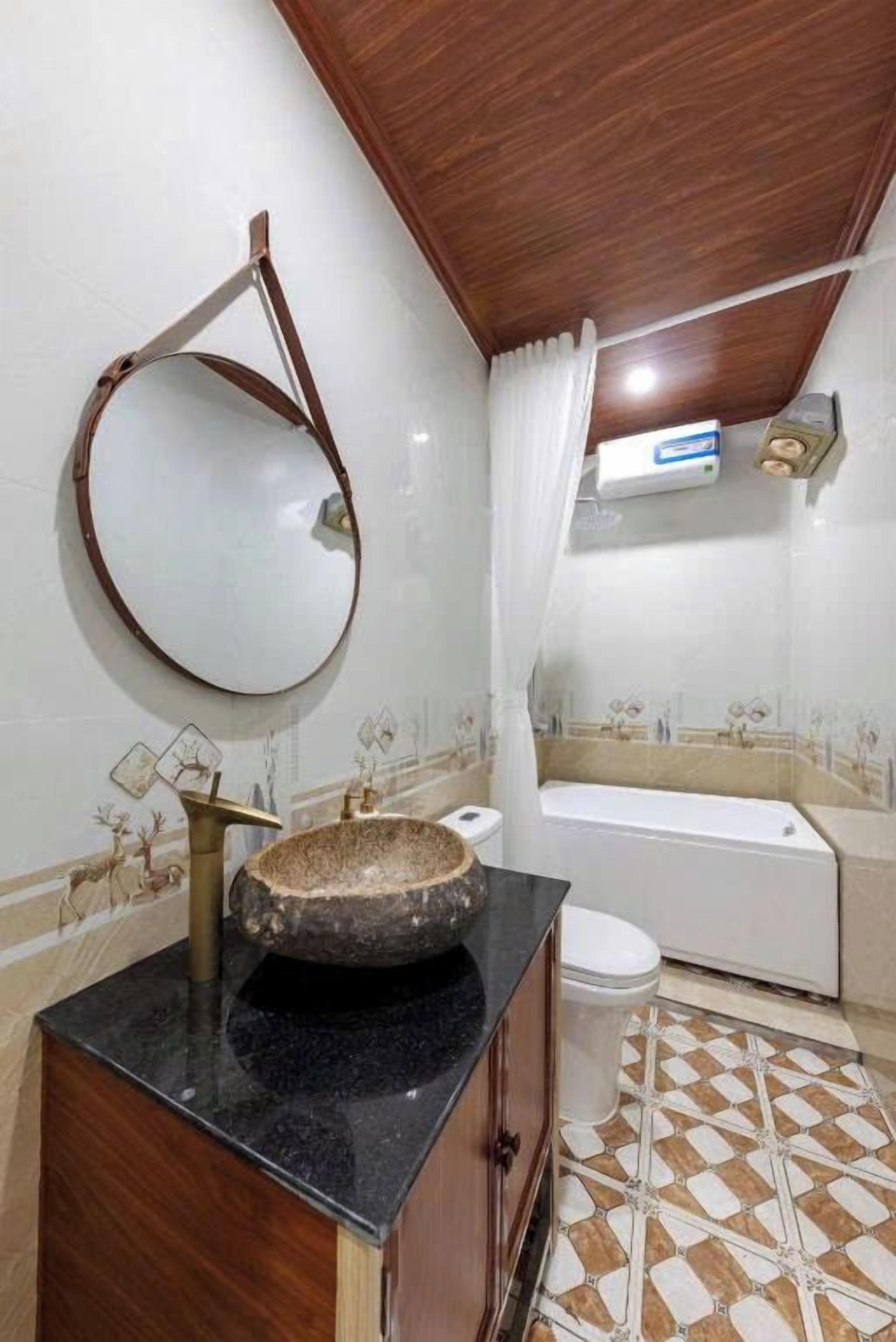 A bathroom with a stone sink, a mirror, a bathtub, and patterned tiles.
