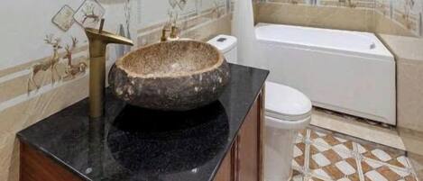 Un baño con lavamanos de piedra, un espejo, una bañera y baldosas estampadas.