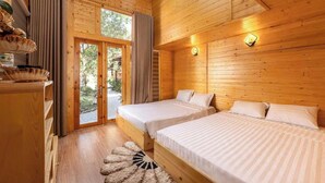 Eine Holzhütte mit zwei Betten, einer Essecke und einer Glastür zum Außenbereich.