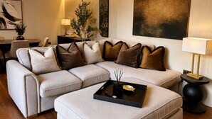 A modern living room with a sectional sofa, a coffee table, and a dining area. - Cedar House at The Old Fire Station (Canterbury)