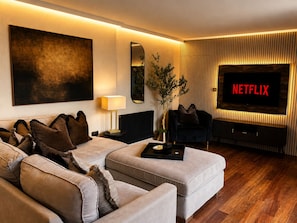 A modern living room with a sofa, a coffee table, a TV, and a plant. - Cedar House at The Old Fire Station (Canterbury)