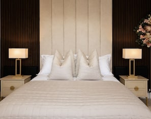 Een hotelkamer met een groot bed, twee nachtkastjes en een hoofdbord met verticale lamellen.