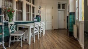 A kitchen with a dining table, chairs, a vase with flowers, and a clock on the wall. - Casa Balcescu (Brasov)