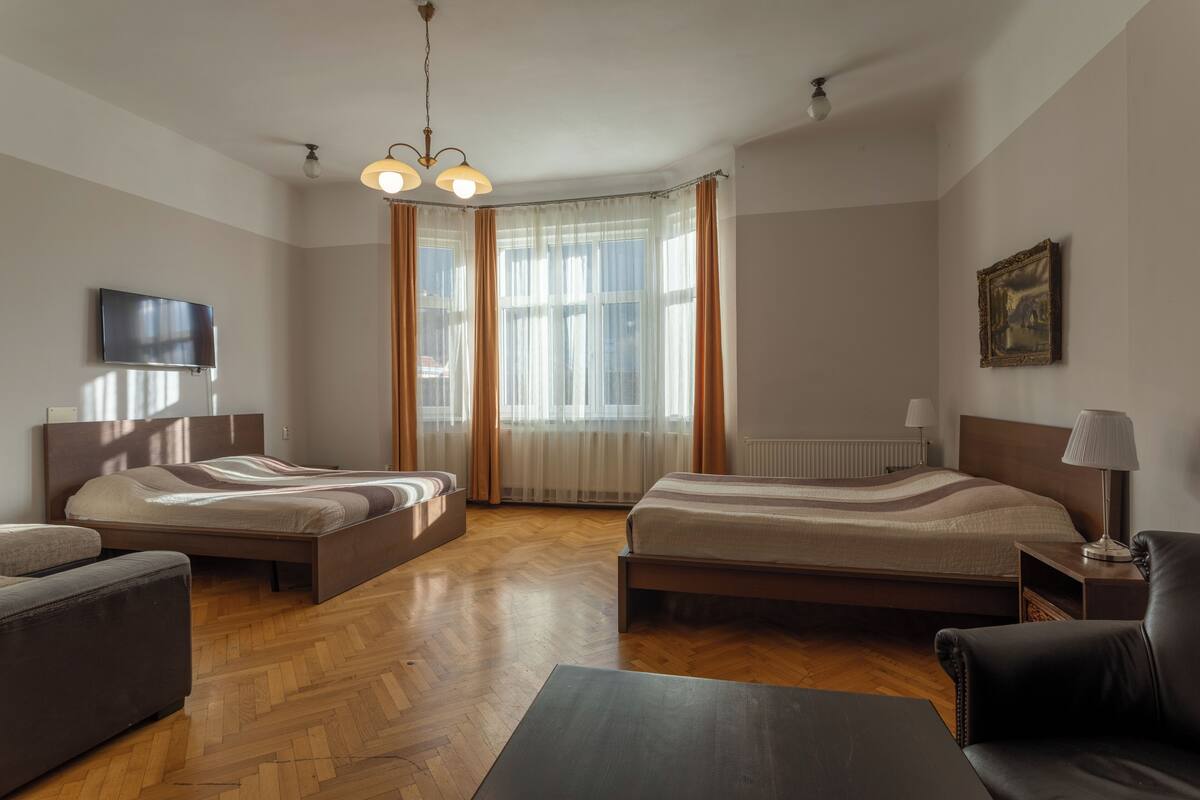 A room with two beds, a TV, a lamp, and a painting on the wall.