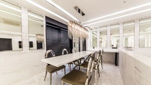 A modern dining area with a long white table, multiple chairs, and a decorative chandelier. - Hotel Forestar (Seoul)
