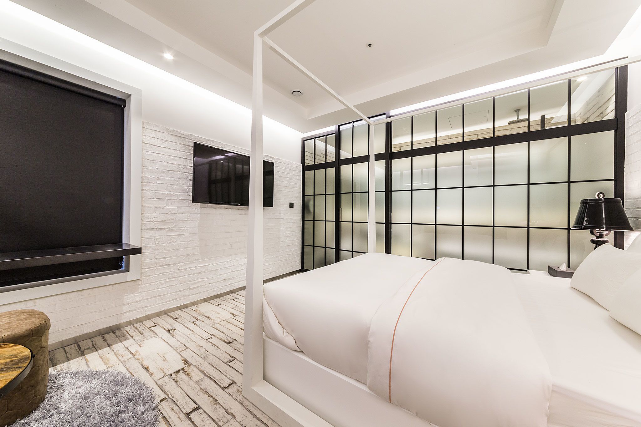 Ein modernes Schlafzimmer mit einem großen Bett, einem an der Wand montierten Fernseher und einem Fenster mit Blick nach draußen.