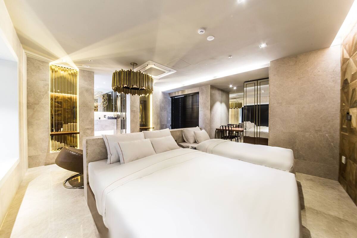 Una habitación de hotel moderna con una cama grande, un área de estar con una mesa y un espejo grande.