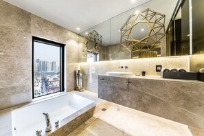 A modern bathroom with a large bathtub, a sink, and a window offering a city view. - Hotel Forestar (Seoul)