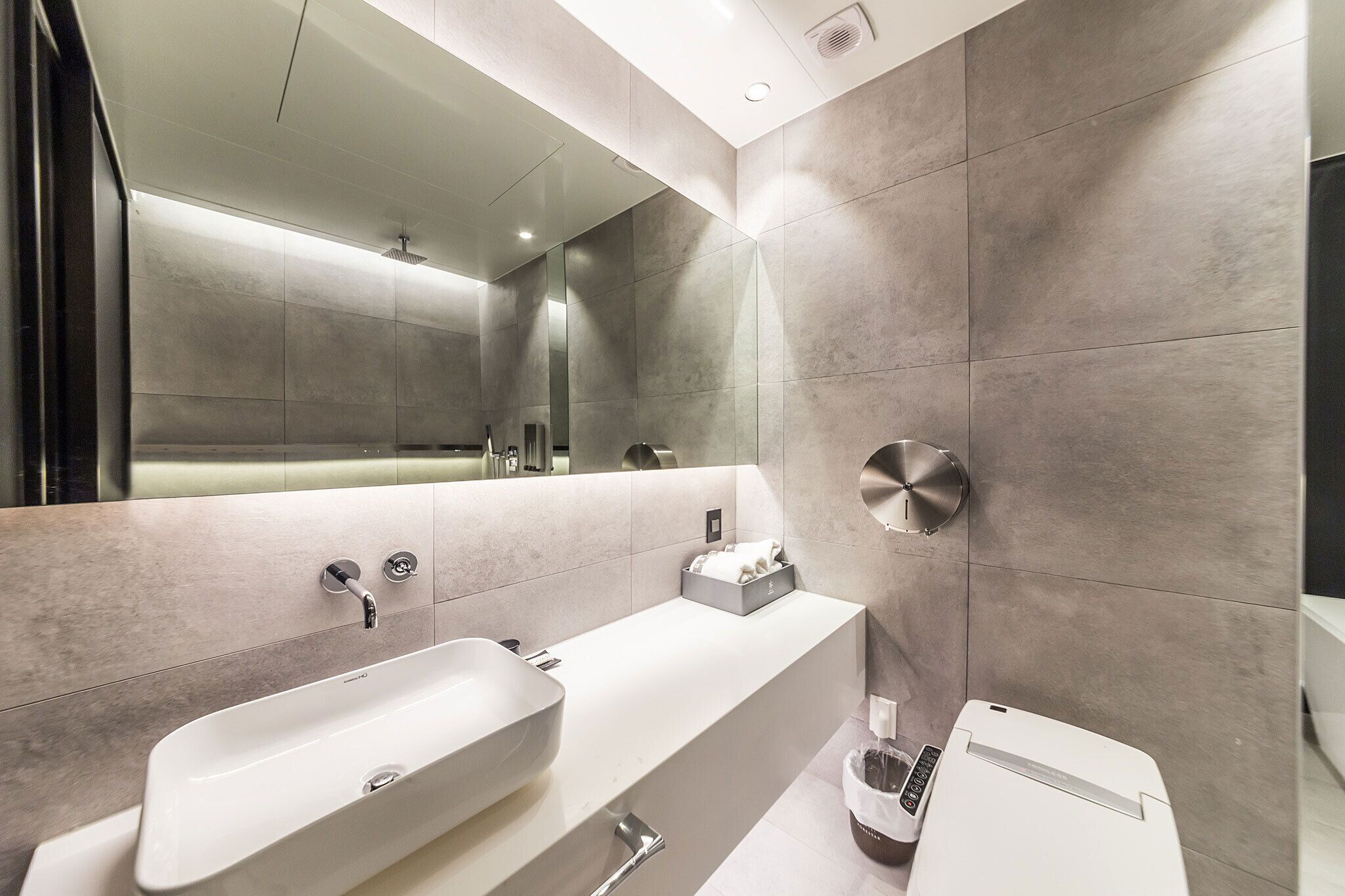 A modern bathroom with a large mirror, two sinks, and a towel rack.