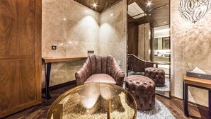 A modern room with a plush armchair, a glass-top table, and tufted ottomans. - Hotel Forestar (Seoul)