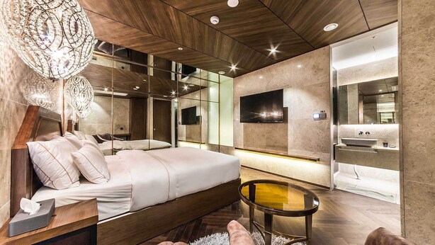 A modern bedroom with a large bed, a bedside table, a round coffee table, and a chandelier. - Hotel Forestar (Seoul)