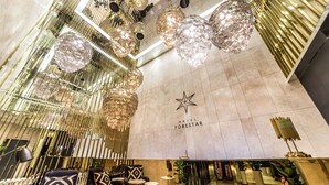 A hotel lobby with a star logo, modern chandeliers, and contemporary furniture. - Hotel Forestar (Seoul)