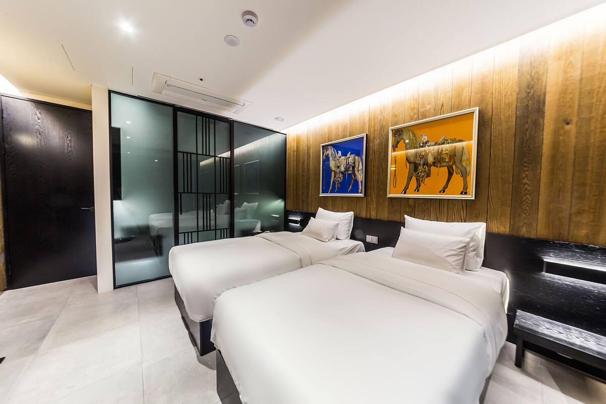 Una habitación de hotel moderna con dos camas, un panel decorativo de madera y obras de arte.