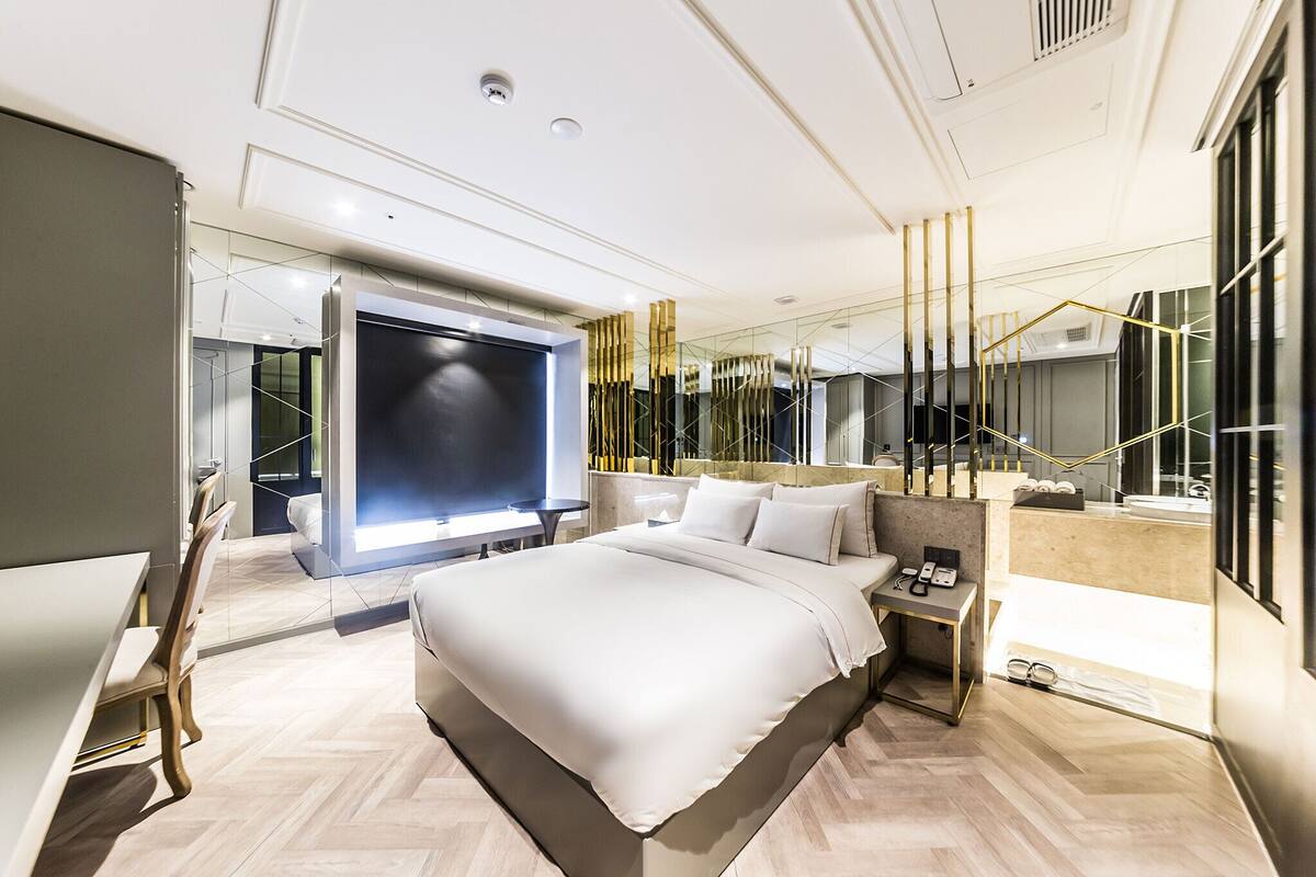 Una habitación de hotel moderna con una cama grande, un escritorio y un televisor.