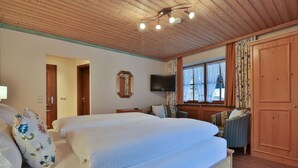 Ein Schlafzimmer mit zwei Betten, einem Fernseher, Holzboden und einem großen Kleiderschrank.