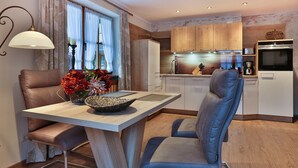 Eine moderne Küche mit Holzschränken, ein Essbereich mit Tisch und Stühlen sowie ein eingebauter Backofen.