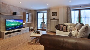 Ein modernes Wohnzimmer mit Flachbildfernseher, einer Holz-Unterhaltungsecke und einer gemütlichen Couch.