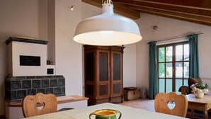 Un comedor con una mesa, sillas, una lámpara colgante grande, un mueble aparador y un ventanal con cortinas.