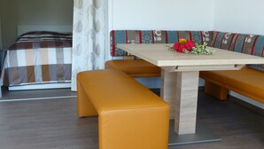 Una habitación con una cama, una mesa de madera y dos bancos naranjas.