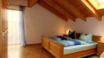 Ein hölzernes Bett in einem Zimmer mit schrägem Dach und Dachfenster.