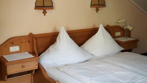 Un dormitorio con una cama de madera, dos mesitas de noche, una lámpara de noche y un jarrón con flores.