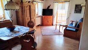 Een gezellige woonkamer met een houten eettafel, stoelen, een bank en een televisie.