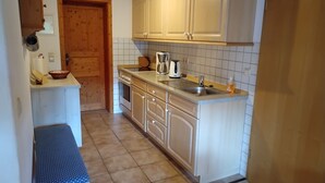 Een kleine keuken met houten kastjes, een inbouwoven en een spoelbak.