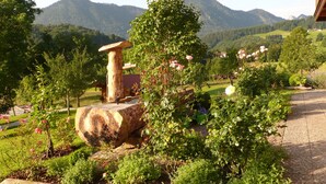 Un jardín con un banco de madera, una mesa de piedra y diversas plantas.