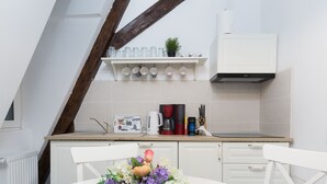 A kitchen with white cabinets, a coffee maker, and a shelf with cups and a plant. - House 54 (Brasov)