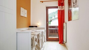 Une petite pièce comprenant un lit, une petite table et une porte donnant sur un balcon.