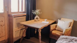A wooden desk with a vase of flowers, a chair, and a window with curtains. - (4) Ferienwohnung 28 qm, Dusche/WC, Kochnische und Balkon (Reit im Winkl)