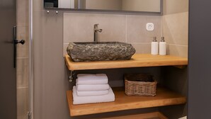 A bathroom with a marble sink, wooden shelves, and a wicker basket. - (4) Ferienwohnung 28 qm, Dusche/WC, Kochnische und Balkon (Reit im Winkl)