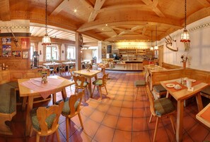Un restaurante acogedor con muebles de madera, piso de baldosas y una zona de bar.