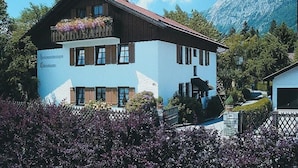 A two-story building with a blue facade and a wooden upper floor. - Stylish apartment with beautiful mountain scenery (St5)/Steilhofweg. 65 sqm, south-facing balcony (Bayerisch Gmain)