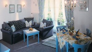 A living room with a sofa set, a coffee table, a dining table with chairs, and a chandelier. - Stylish apartment with beautiful mountain scenery (St5)/Steilhofweg. 65 sqm, south-facing balcony (Bayerisch Gmain)