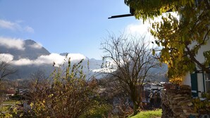A mountainous landscape with a clear sky, a stone wall, and a building with a green door. - Alpenhof Punzenlehen (Schoenau am Koenigssee)