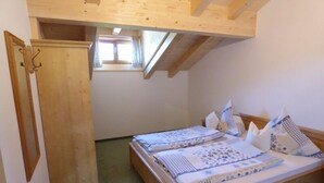 Un dormitorio pequeño y acogedor con una cama nido de madera, un ventanal y una puerta.