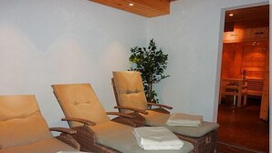 Un cuarto de spa con tres sillones de mimbre, cada uno con cojín y una toalla doblada.
