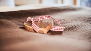 A wooden object with a red and white checkered ribbon tied around it, placed on a textured fabric surface. - (204) Ein-Raum-Ferienwohnung (Reit im Winkl)