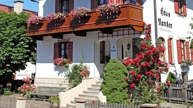 A traditional Alpine-style building with a steeply pitched roof, wooden balconies with flower boxes, and a sign reading "Haus Hahnerz". - (204) Ein-Raum-Ferienwohnung (Reit im Winkl)