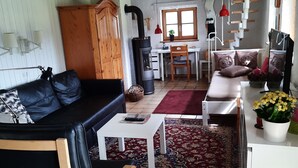 Een gezellige woonkamer met een bank, een salontafel en een vloerkleed. Er is een houten kast en een open haard.