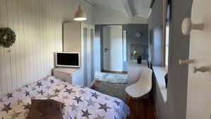 Een slaapkamer met een bed, een televisie, een bureau en een stoel.