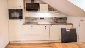 A compact kitchen with white cabinetry, a built-in oven, and a dark countertop.