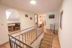 A staircase with metal railings leading to a second-floor area with a dining table and chairs.