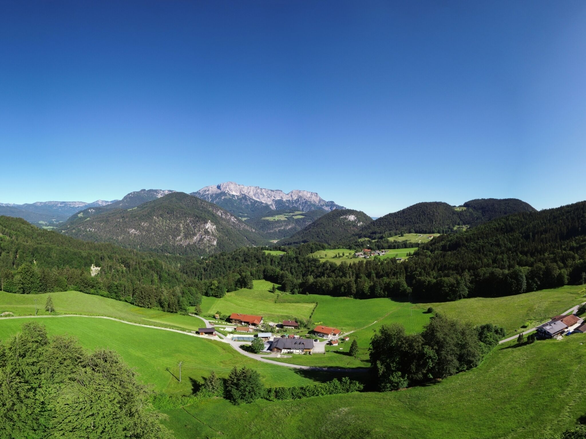 A rural landscape with a small village, green fields, and mountains in the background.